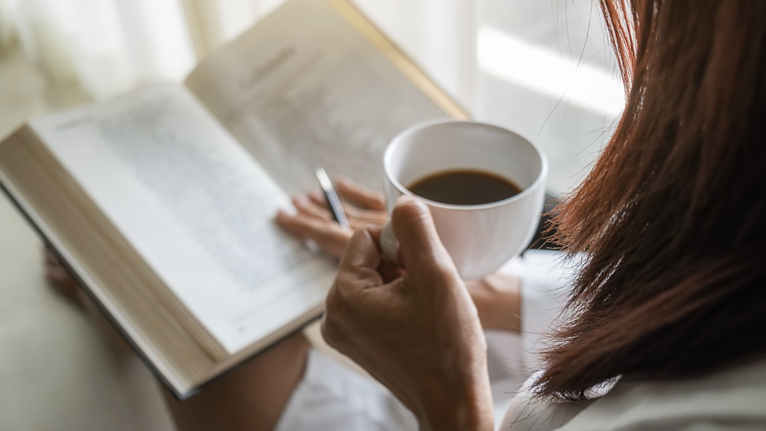 woman reading while drinking coffee
